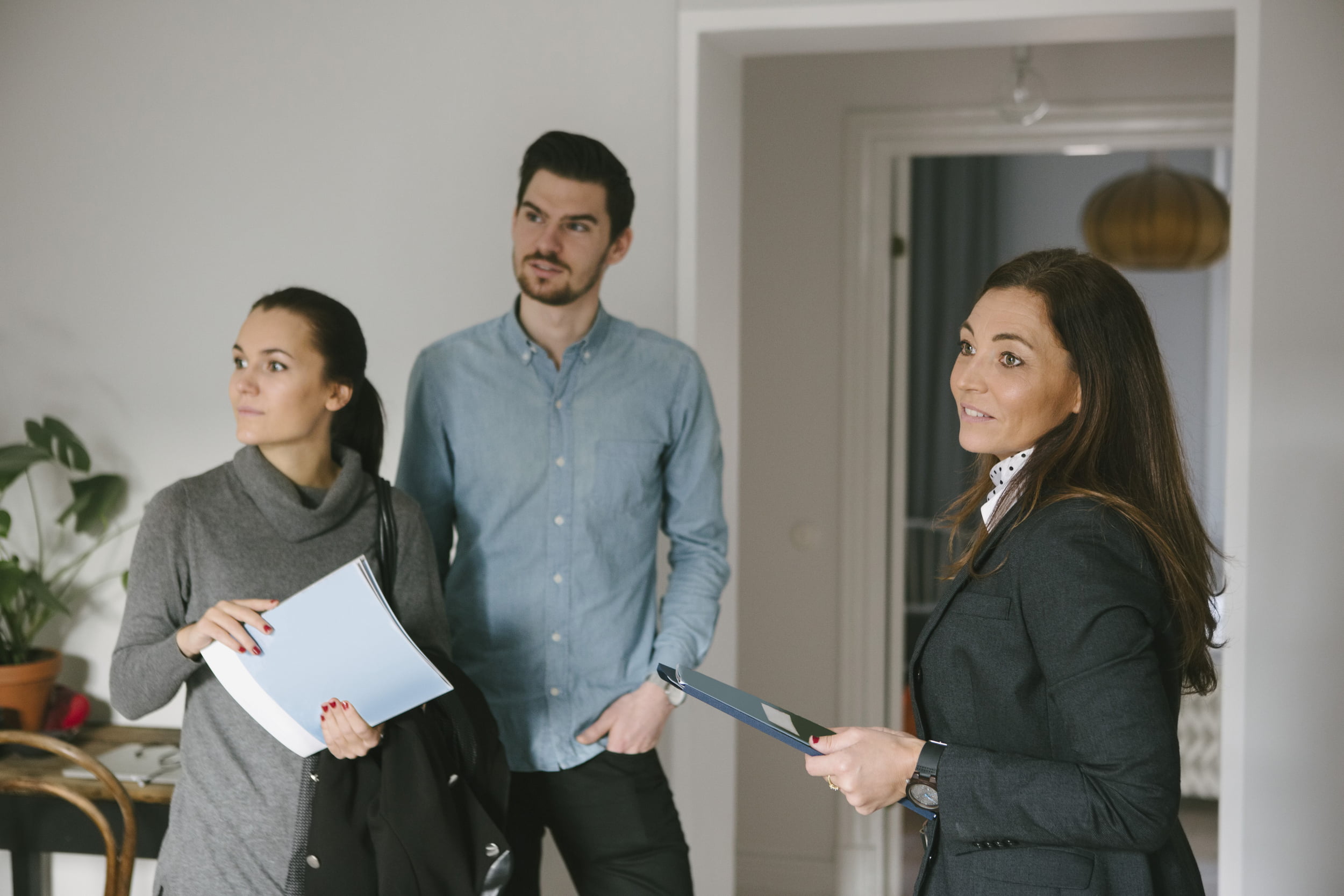 Et ungt par er på visning og snakker med megler